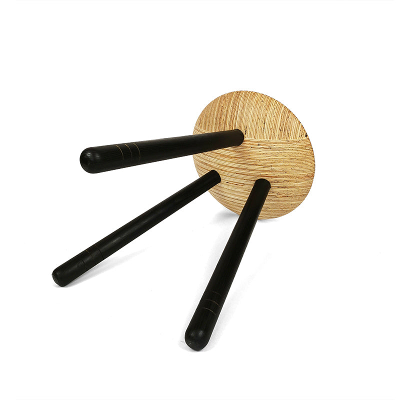 Gedrechselter Dreibeinhocker mit schwarzen Beinen, liegend.