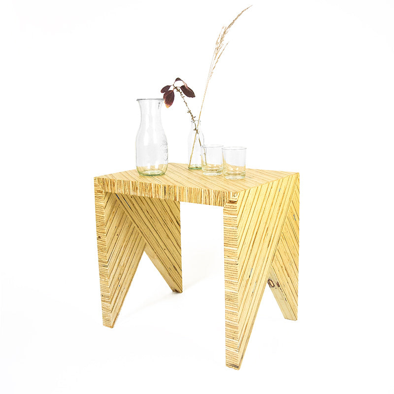 ein Hocker aus Bauholzplatte mit Vase und Gläsern
