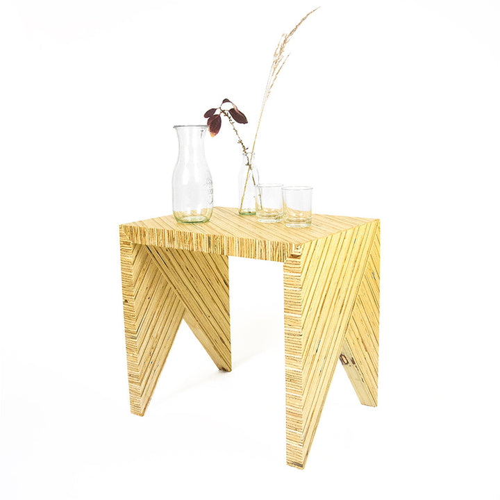 ein Hocker aus Bauholzplatte mit Vase und Gläsern